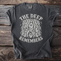 Dark grey t-shirt with "The Deep Remembers" and a cluster of eyes graphic.