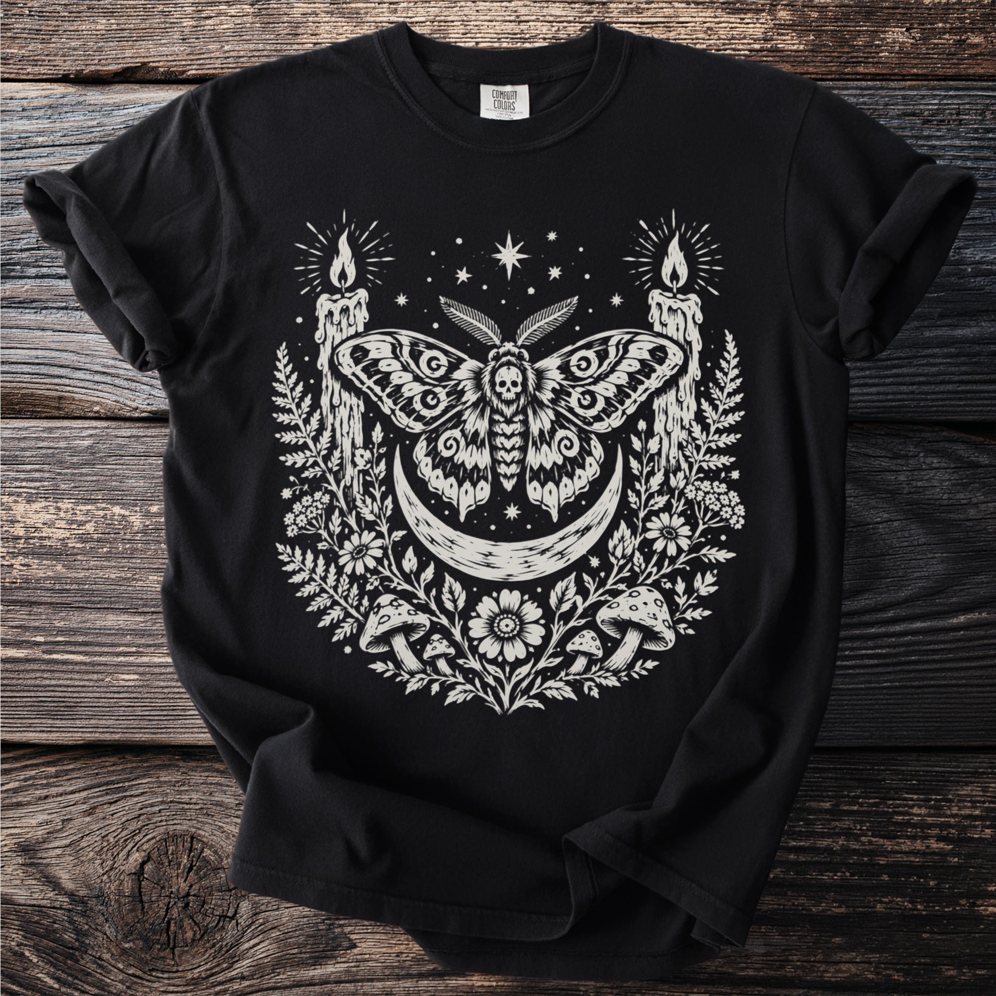 Black Comfort Colors t-shirt with a white moth, moon, candles, and floral design.