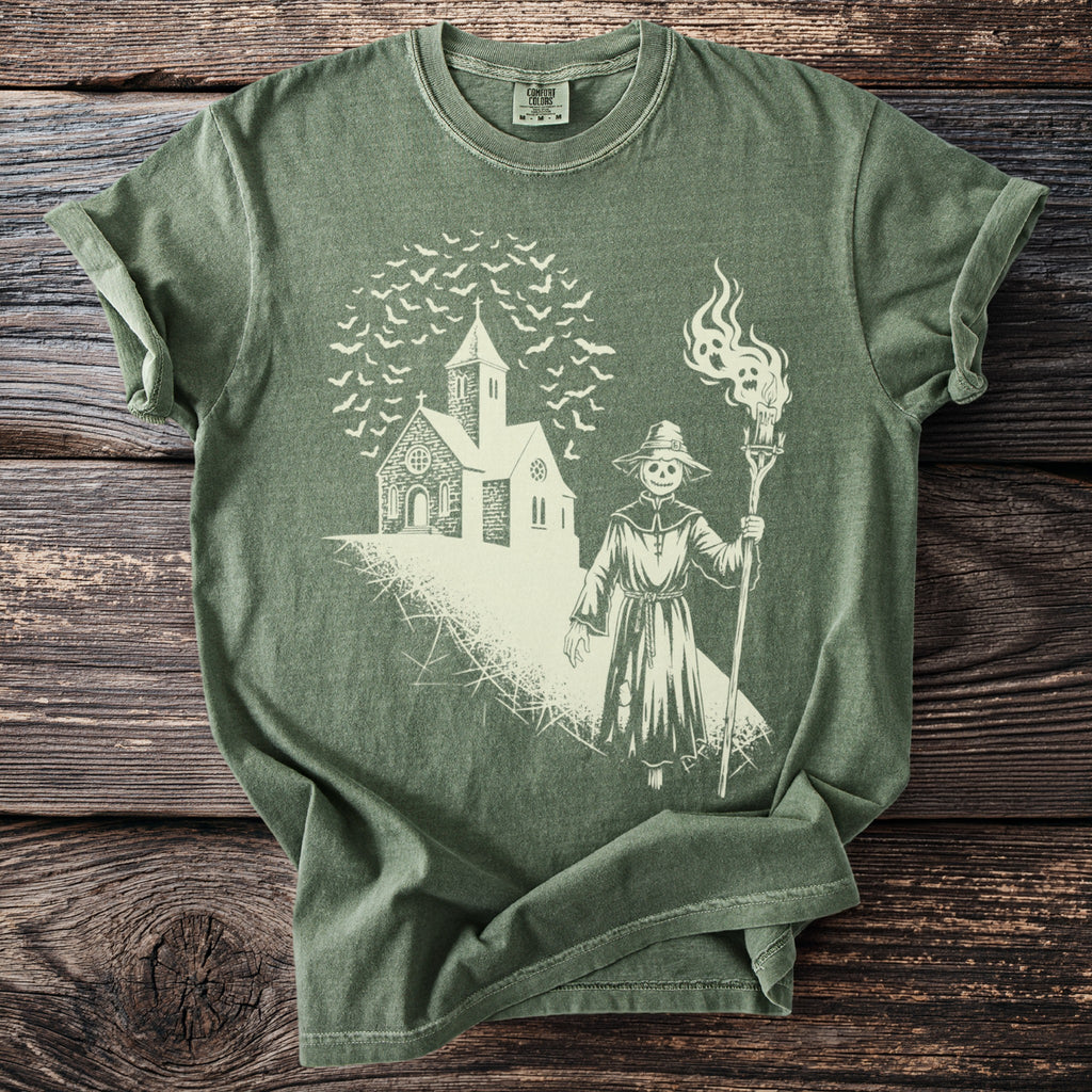Green t-shirt with a sketch of a scarecrow, church, and bats.