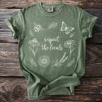 Green t-shirt with white line art of a bee, butterfly, flowers, and text "respect the locals".