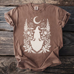 Brown t-shirt with a witch silhouette surrounded by crescent moon, stars, and botanical elements.