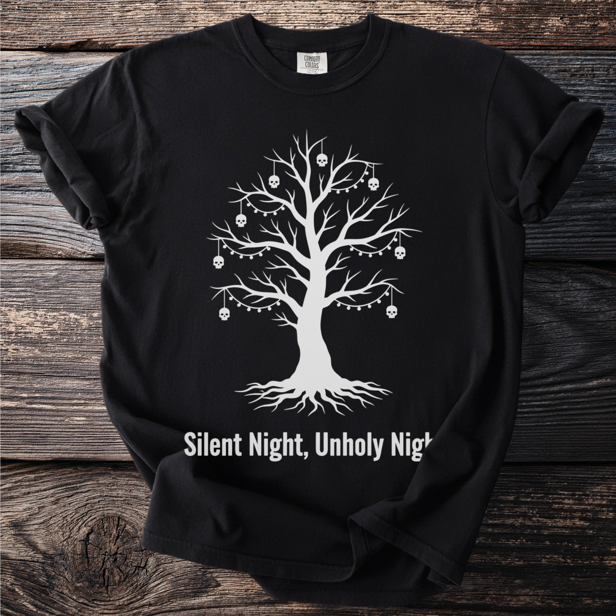Black t-shirt with white illustration of a bare tree with skull ornaments and "Silent Night, Unholy Night" text.