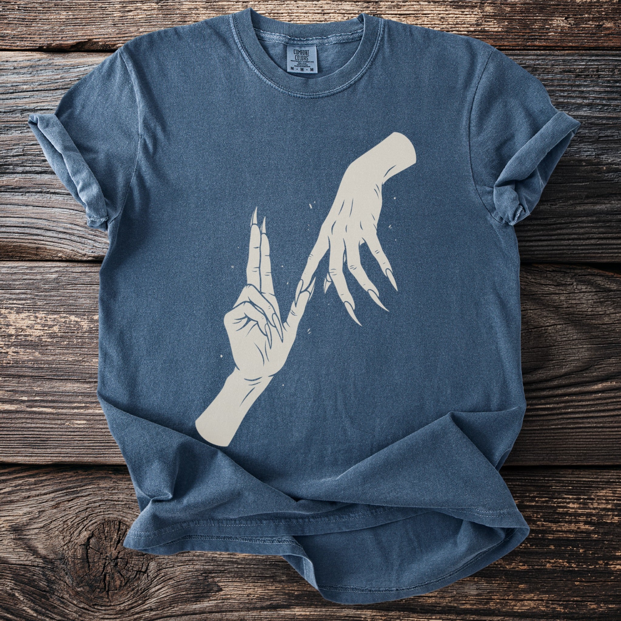 Blue t-shirt with a graphic of two stylized hands with long fingernails.