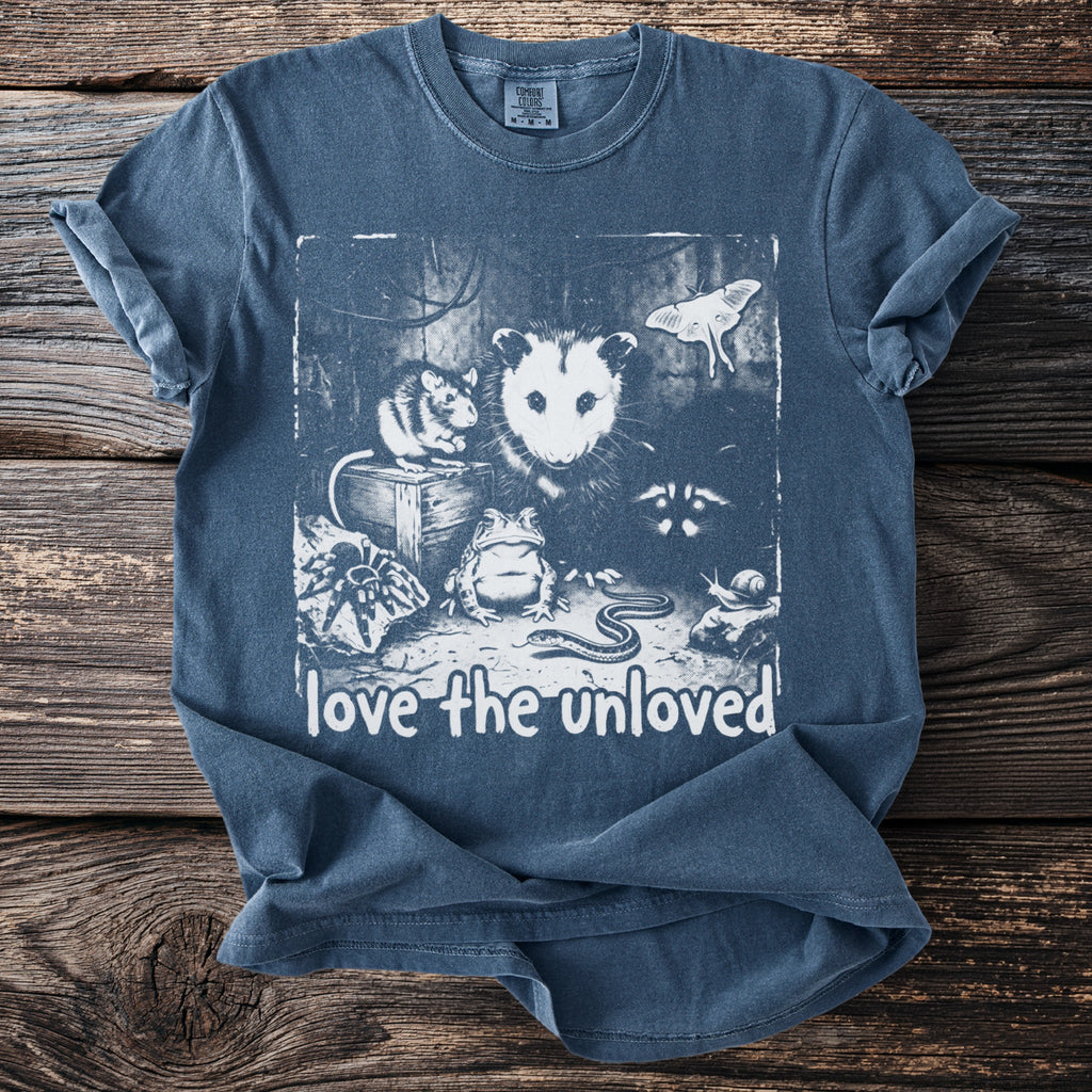 T-shirt with a graphic featuring an opossum, mouse, frog, snake, moth, spider, raccoon, and snail, with text "love the unloved."