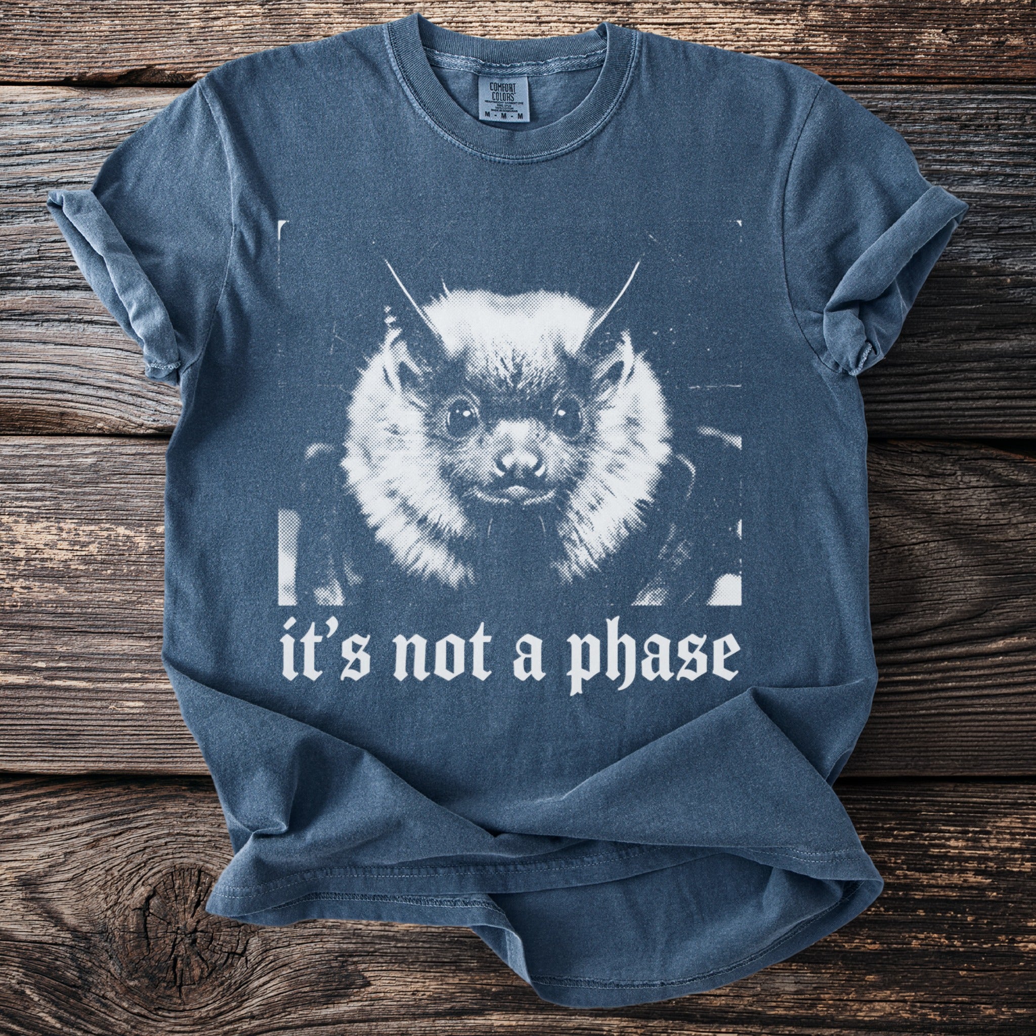 Blue t-shirt with distressed print of a bat face and the text "it's not a phase".