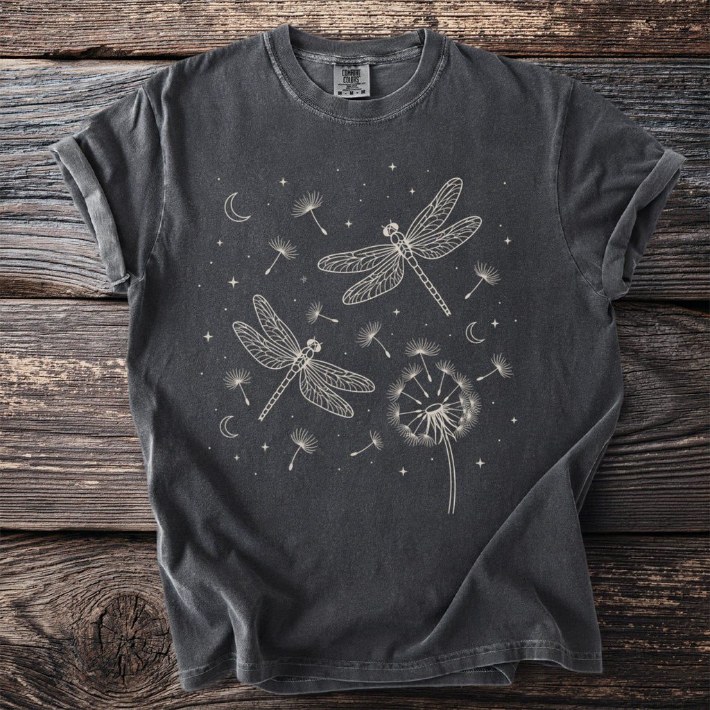 Dark gray t-shirt with cream line art of dragonflies, dandelions, moons, and stars.