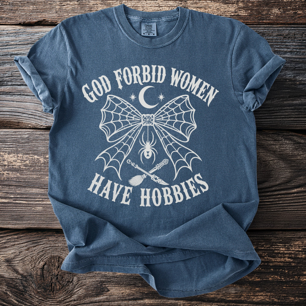 Blue t-shirt with white text "GOD FORBID WOMEN HAVE HOBBIES" and spider web graphics.