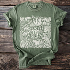 Green t-shirt with white illustration of rainforest animals and text "respect the locals".