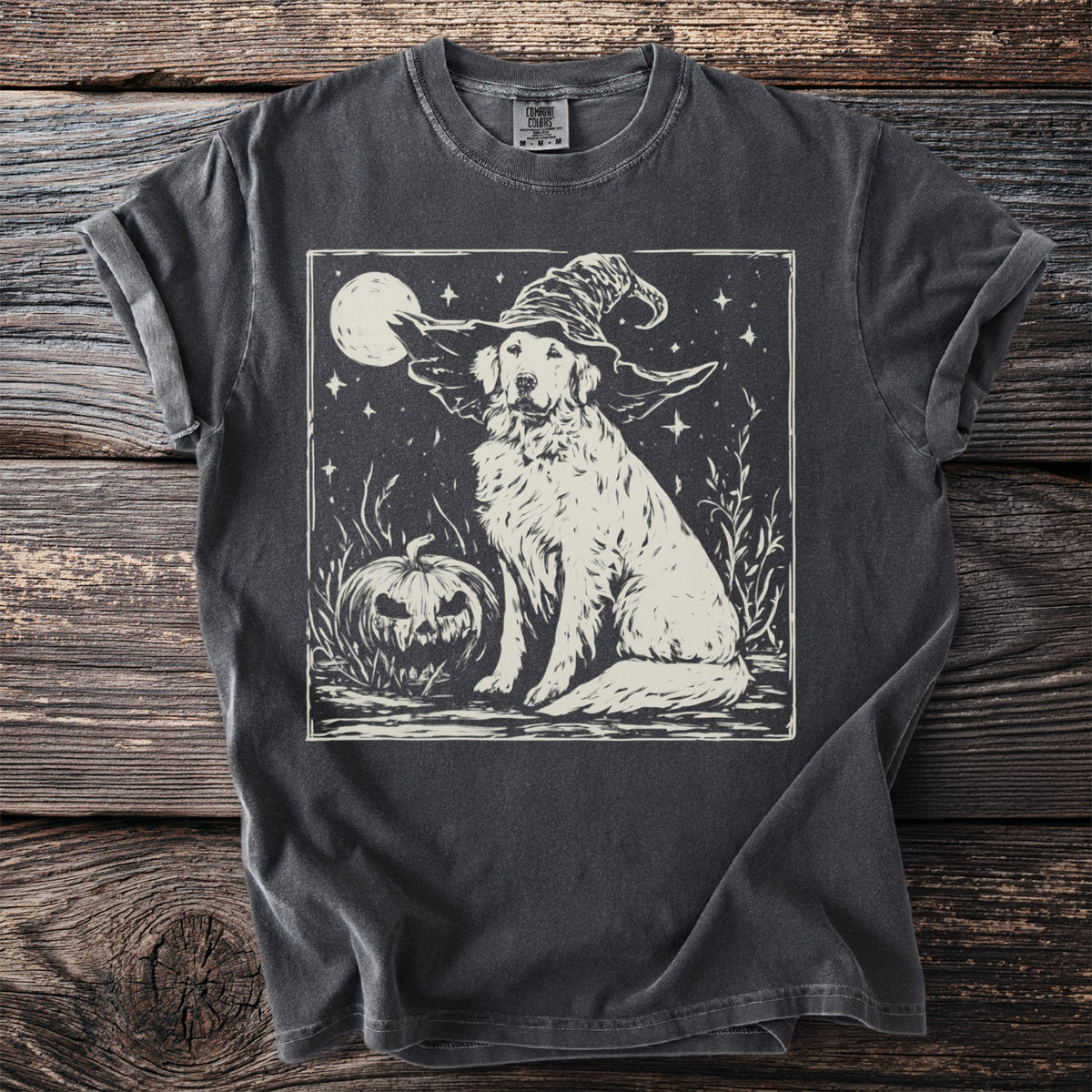Golden retriever wearing a witch hat with pumpkin and moon on a black t-shirt.