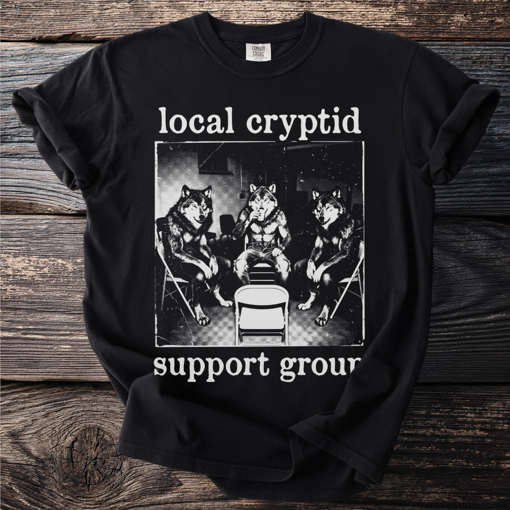 T-shirt with "local cryptid support group" text and image of three anthropomorphic wolves in a meeting.