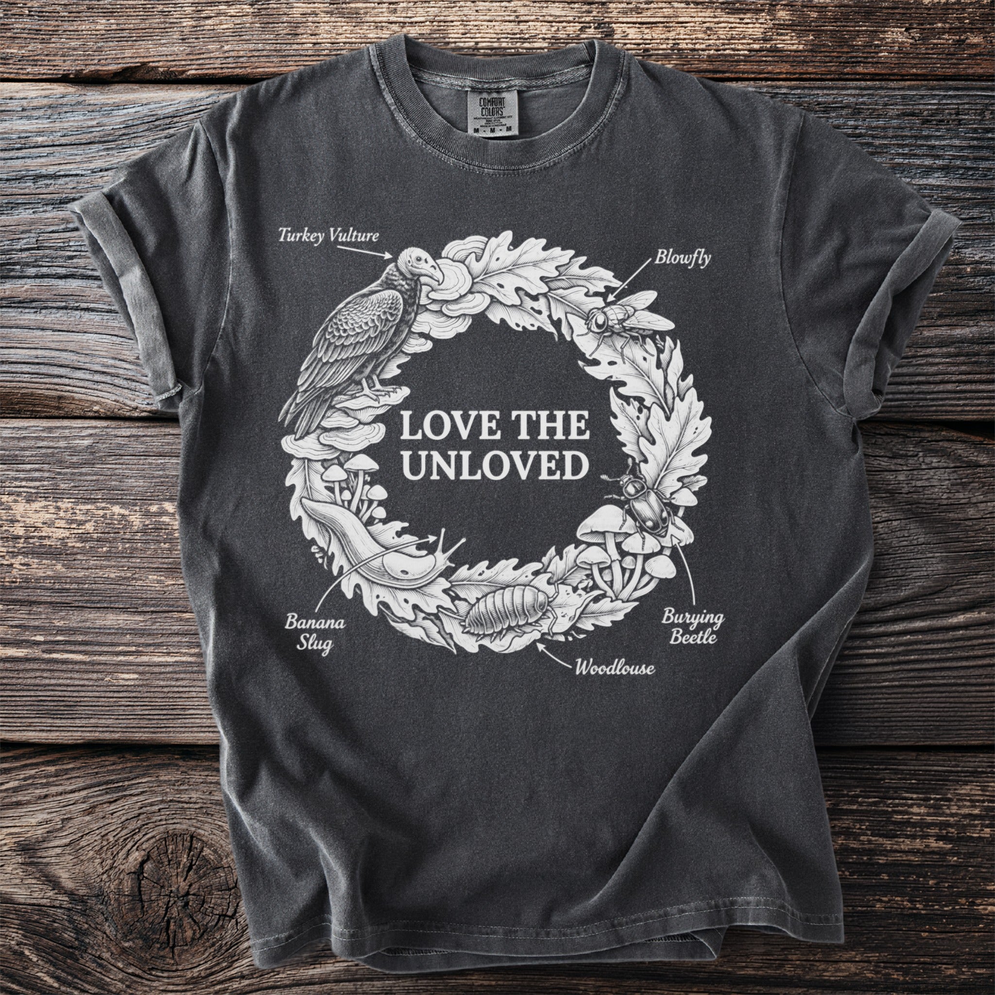 Dark grey t-shirt with "LOVE THE UNLOVED" and a wreath of bugs, slugs, and mushrooms.