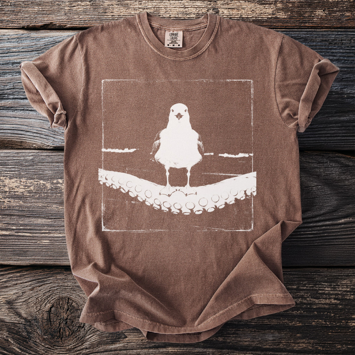 Brown t-shirt with a white graphic of a seagull on octopus tentacles.