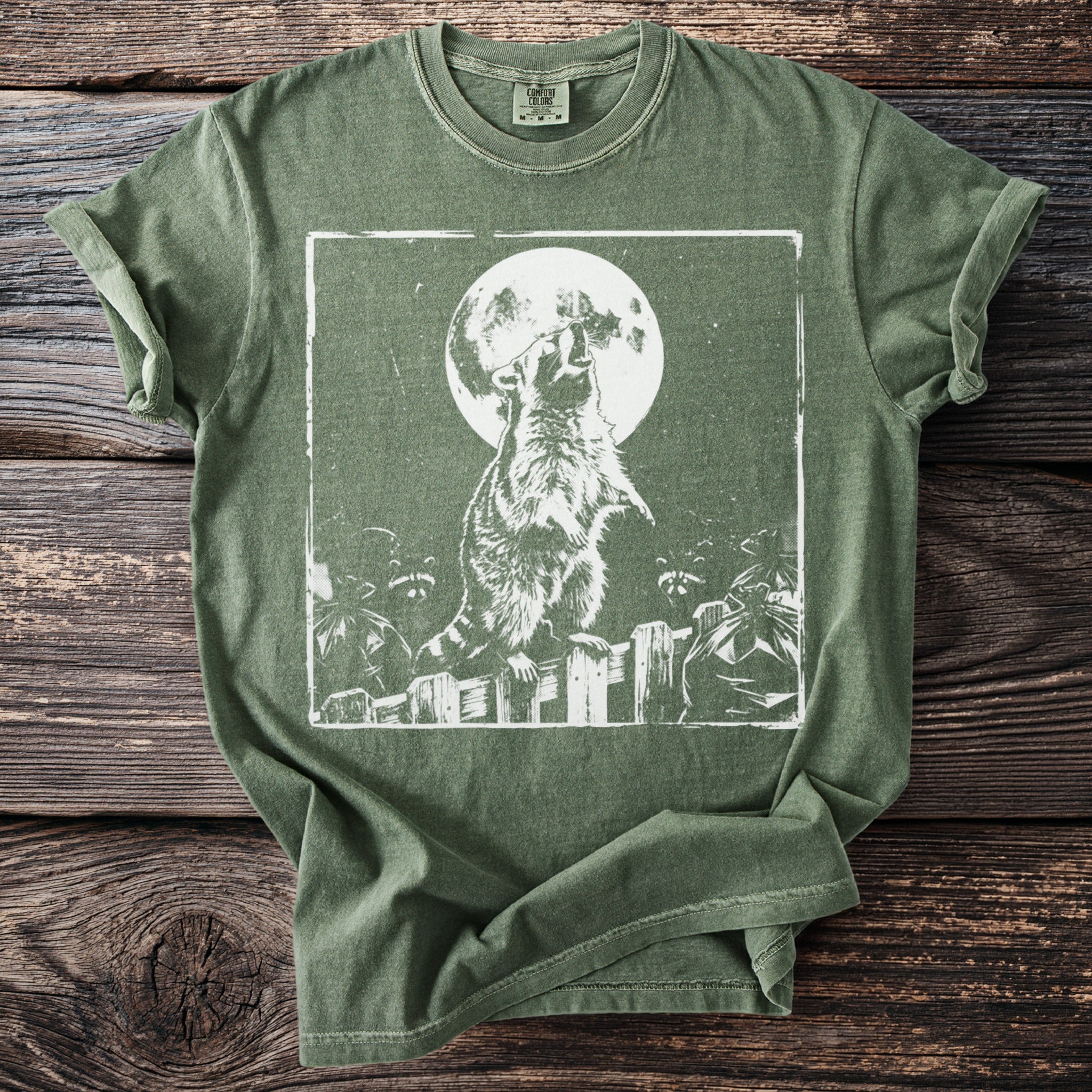 Green t-shirt with a graphic of a raccoon in front of a full moon.