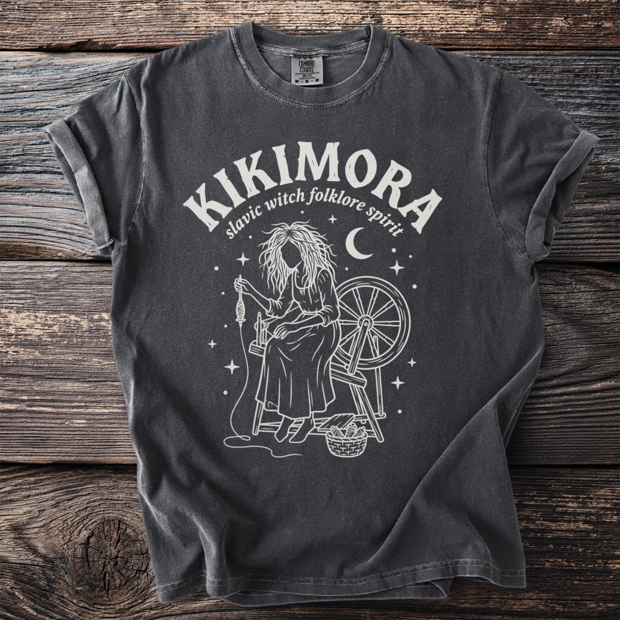 Dark gray Comfort Colors t-shirt with Kikimora slavic folklore spirit design.