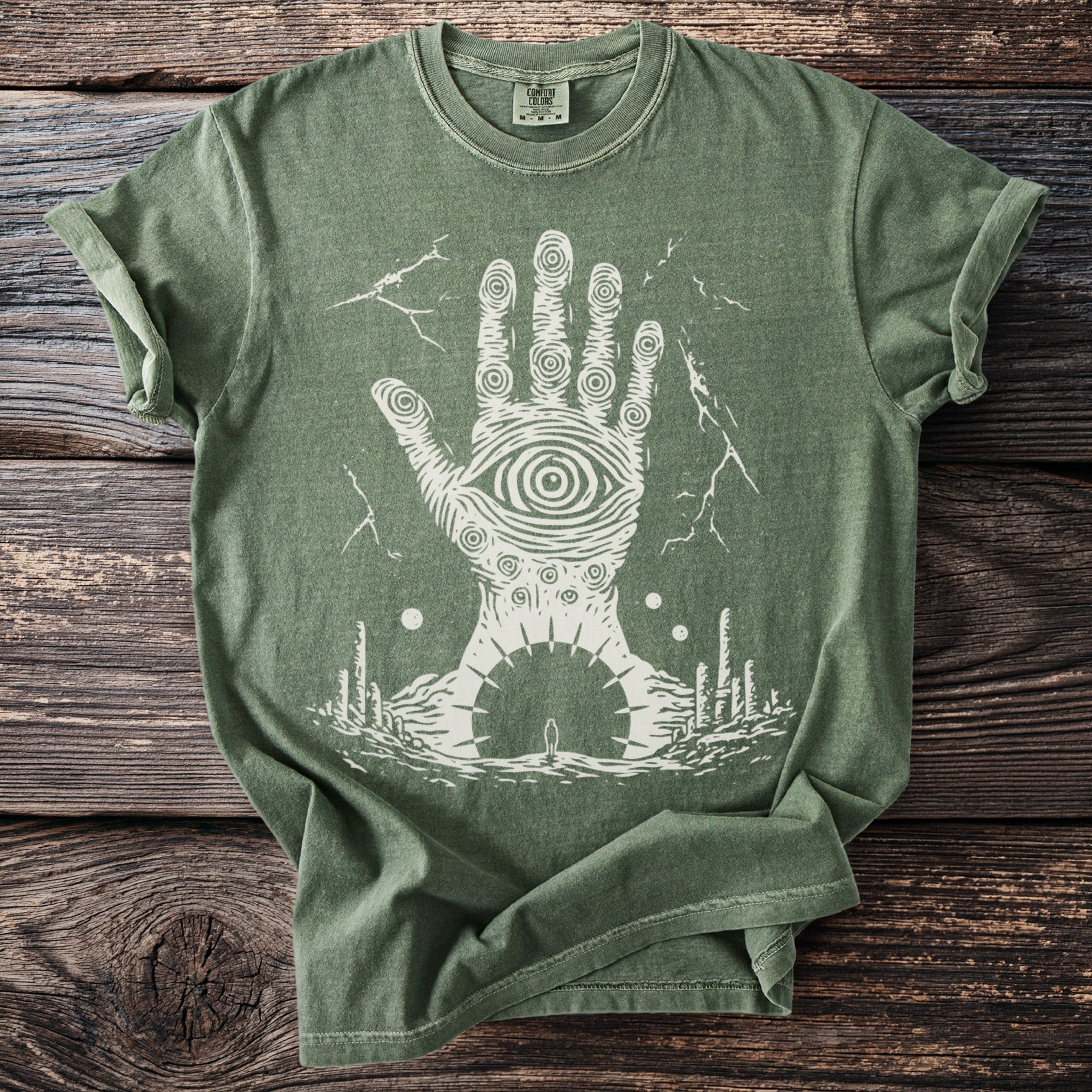 Green t-shirt with a large white eye on a hand with lightning and a landscape.