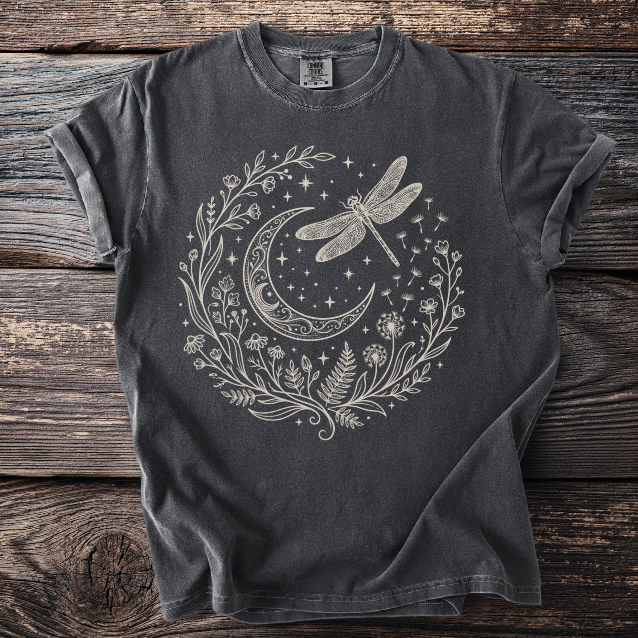 Dark grey t-shirt with a cream-colored design of a crescent moon, dragonfly, and floral elements.