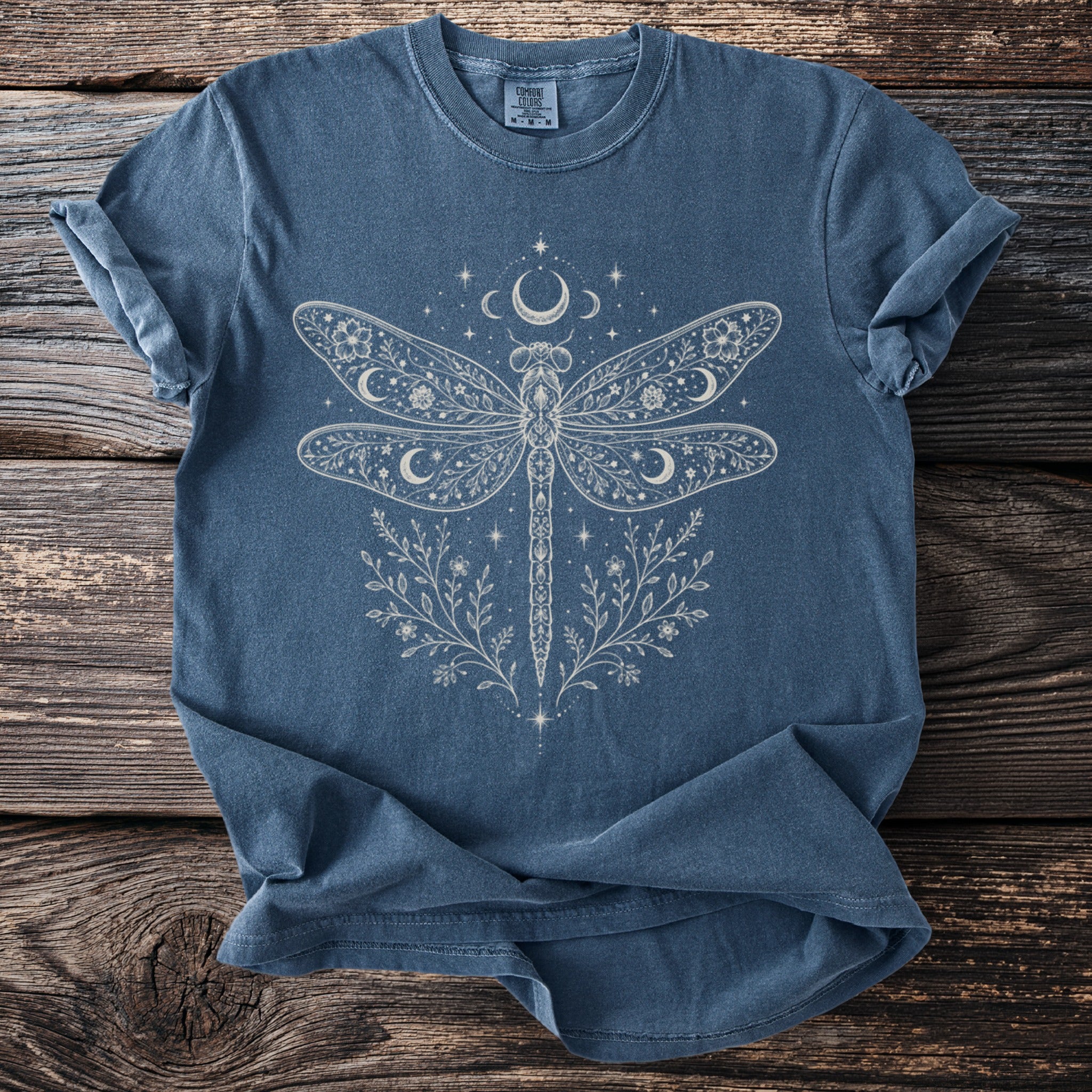 Blue t-shirt with linework dragonfly, moons, stars, and floral design.
