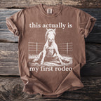 Brown t-shirt with white text and distressed horse graphic: "this actually is my first rodeo"