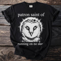 Black t-shirt with white text "patron saint of" above a barn owl and "running on no slee" below