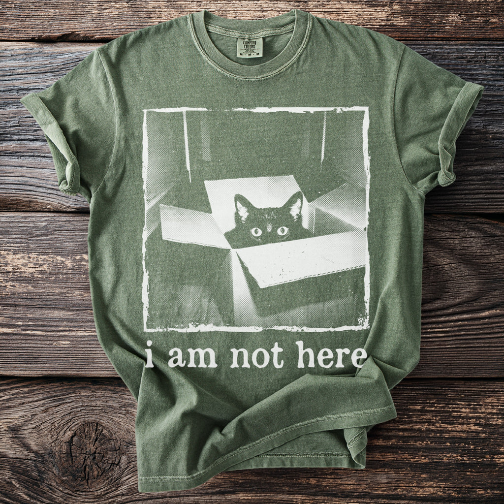 Green t-shirt with a black cat peeking out of a box and text "i am not here".
