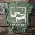 Green t-shirt with a black cat peeking out of a box and text "i am not here".