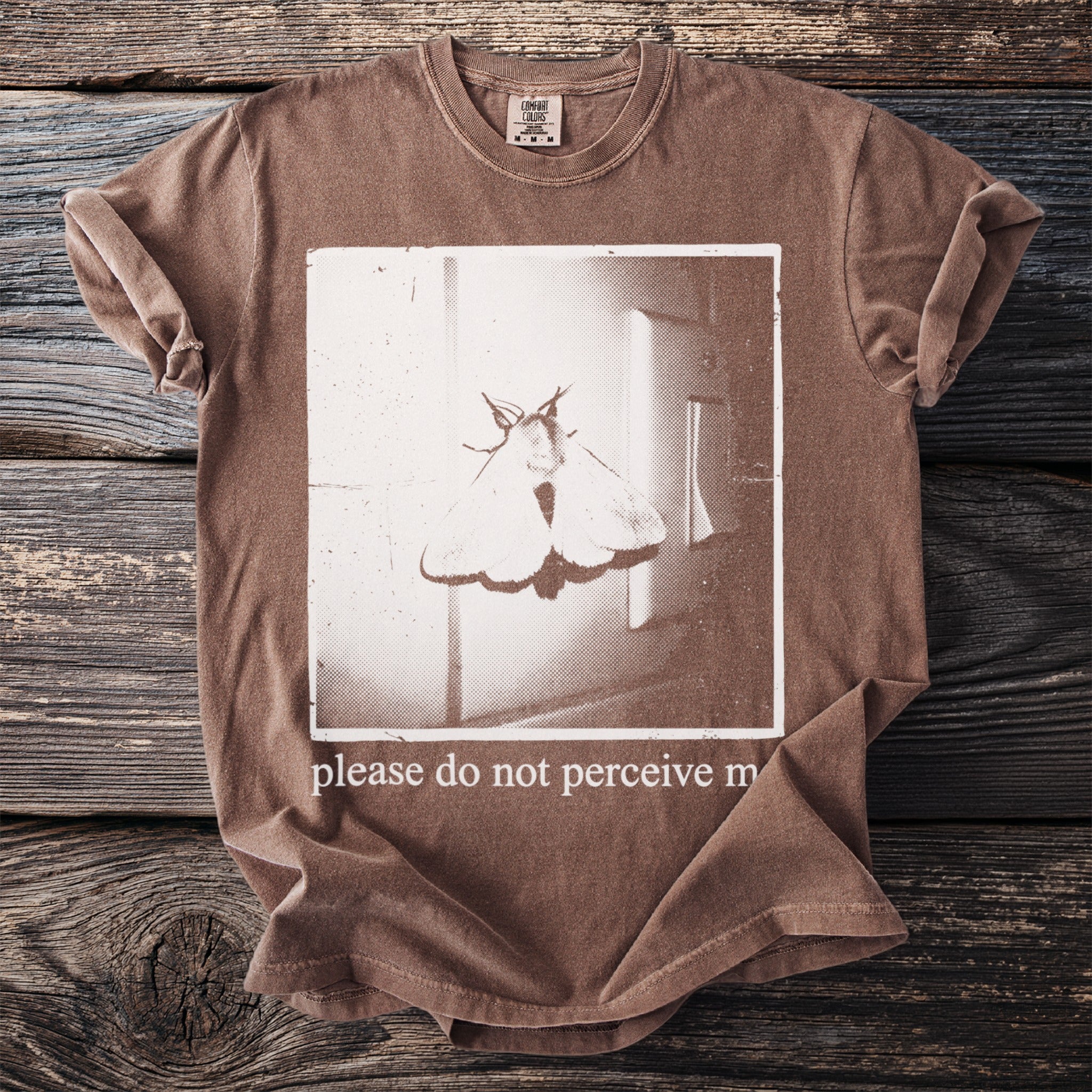 Brown t-shirt with moth graphic and text "please do not perceive m".