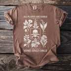 Brown t-shirt with white graphic of skull, crossbones, and plants with text.
