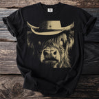 Black t-shirt with a tan graphic of a highland cow wearing a cowboy hat.