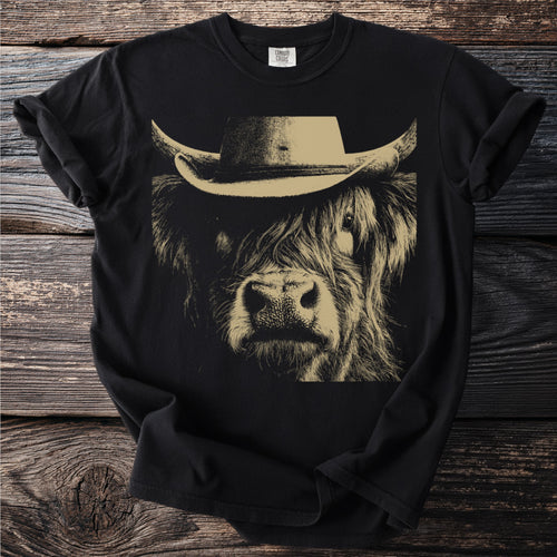 Black t-shirt with a tan graphic of a highland cow wearing a cowboy hat.