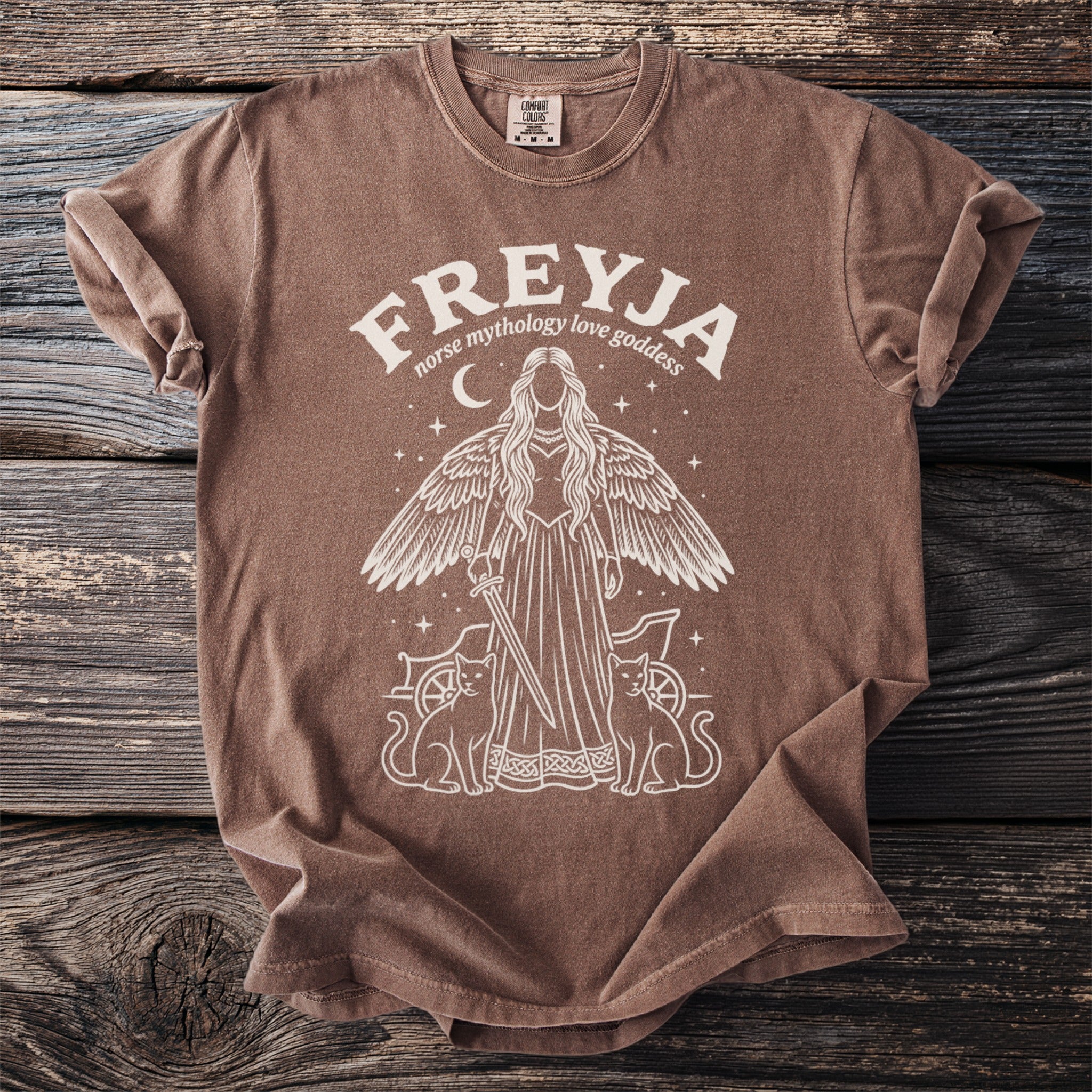 Brown t-shirt with a white graphic of Freyja, Norse goddess of love, with wings and cats.