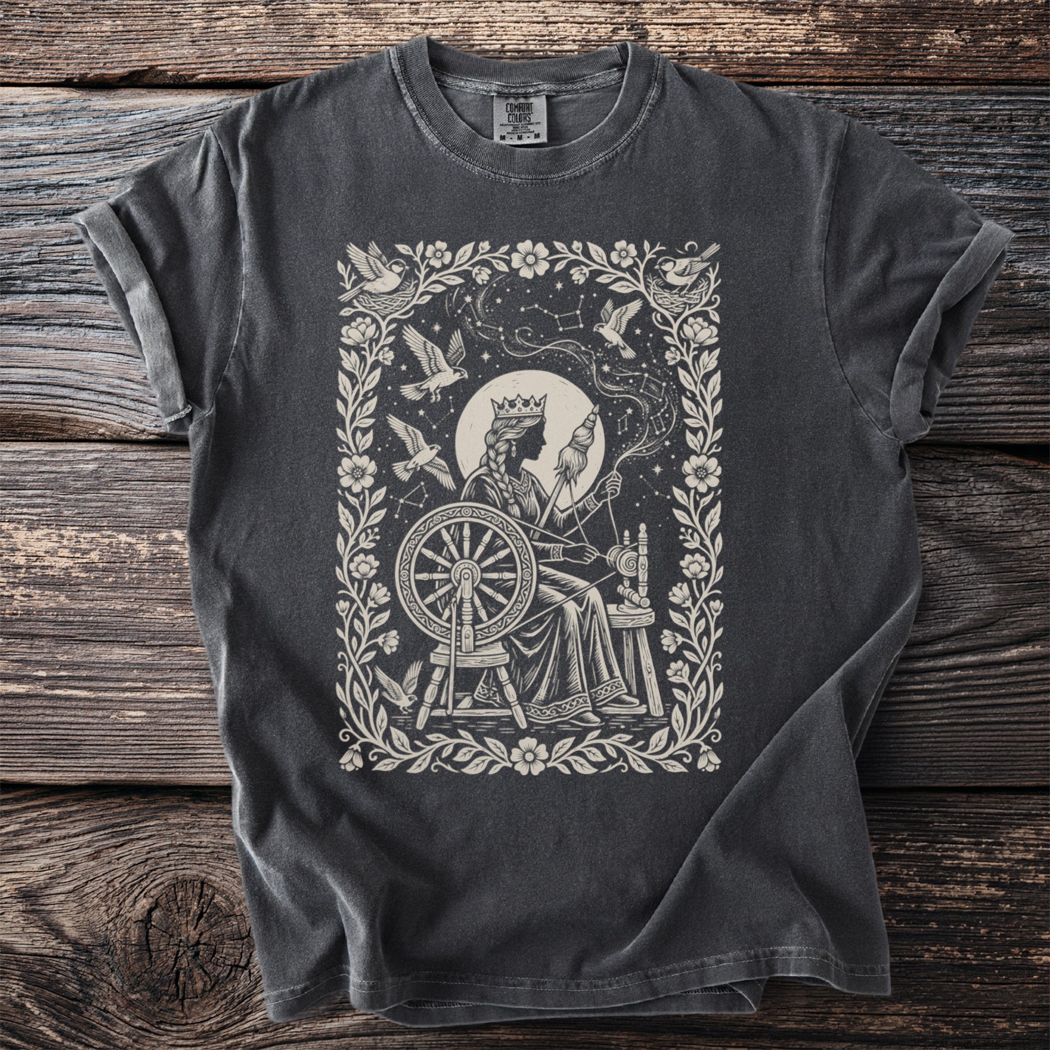 Illustration for a t-shirt featuring a crowned woman spinning by a wheel with birds and stars.
