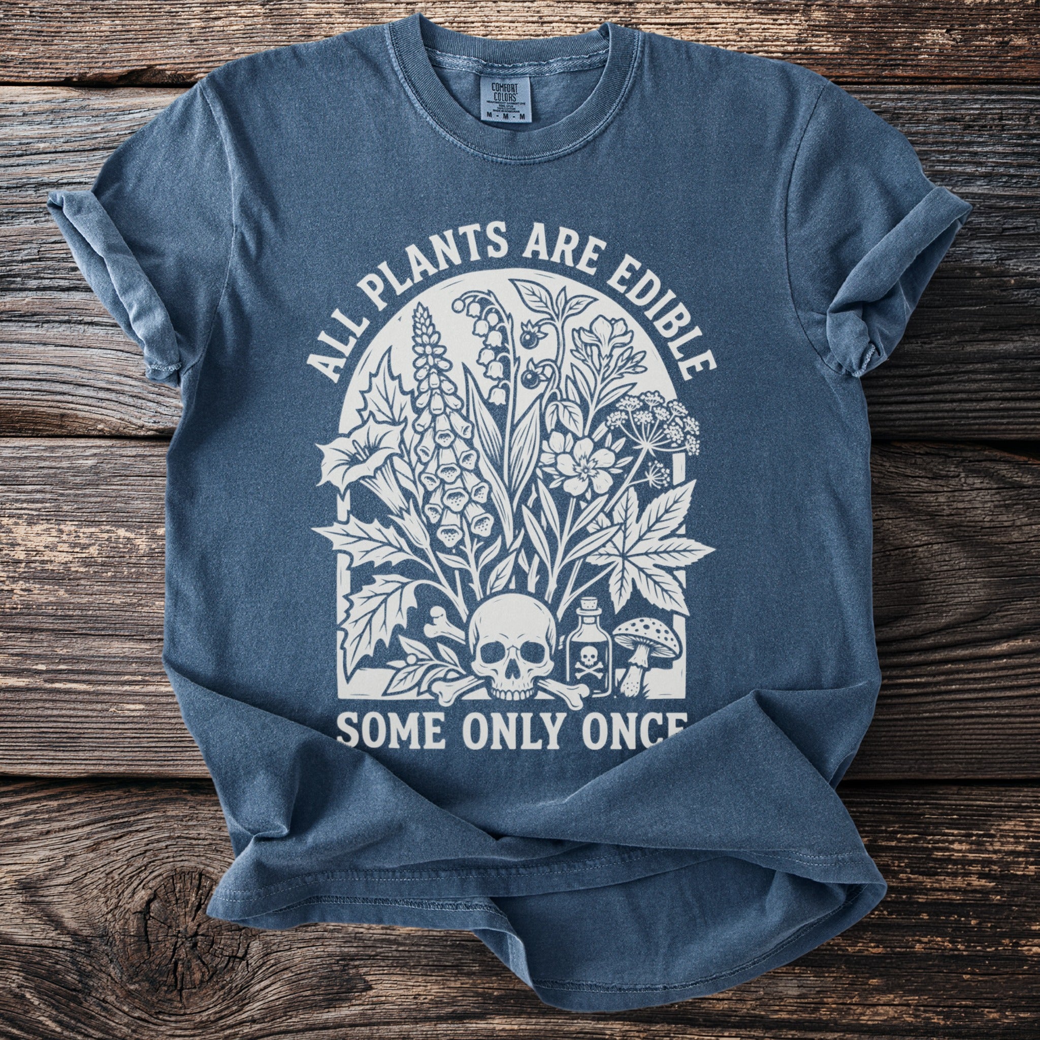Blue t-shirt with white graphic of plants, skull, bones, and poison bottle.