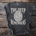 Dark t-shirt with text "THE DEEP REMEMBERS" and an illustration of many eyes.