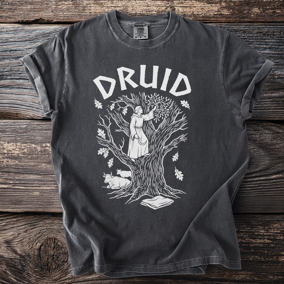 Dark grey t-shirt with white druid graphic on a tree with cows and book.