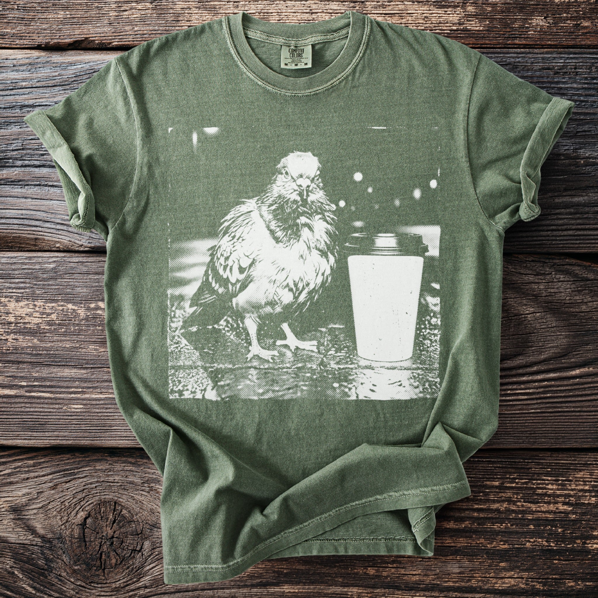 Olive green Comfort Colors t-shirt with graphic of a pigeon and a coffee cup.