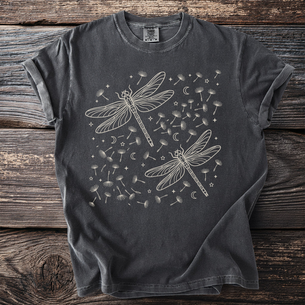 Charcoal t-shirt with two cream line-art dragonflies surrounded by dandelions, moons, and stars.