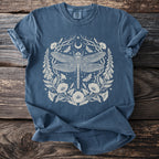 Blue t-shirt with a detailed cream dragonfly, moon, and floral design.