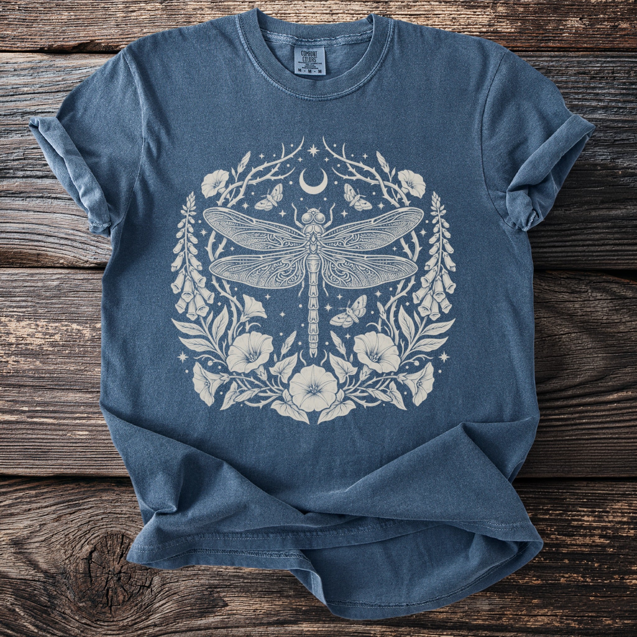 Blue t-shirt with a detailed cream dragonfly, moon, and floral design.