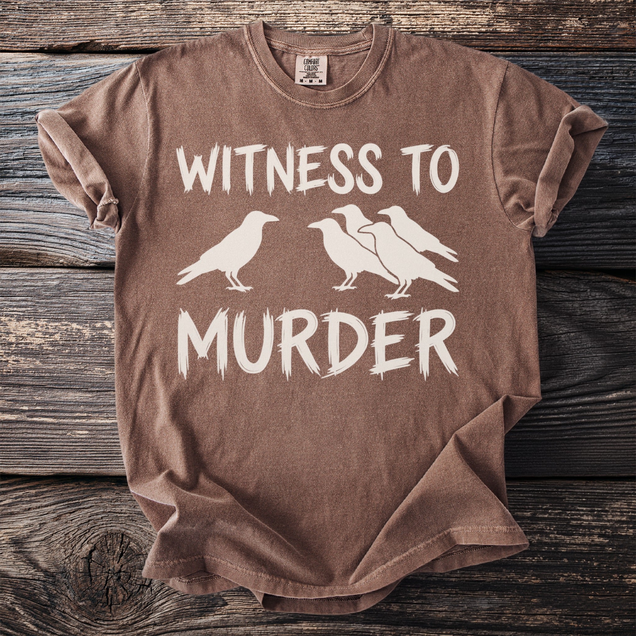 Brown t-shirt with white text "WITNESS TO MURDER" and silhouettes of four crows.