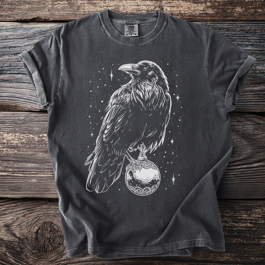 T-shirt with white line art of a crow holding a decorative orb amidst stars.