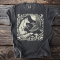 T-shirt with cream illustration of a fox and raven in moonlit forest with mushrooms.