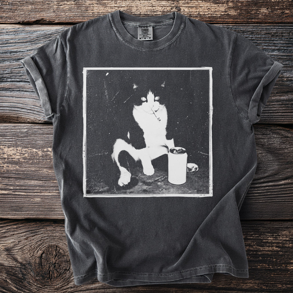 Dark t-shirt with a black and white graphic of a cat sitting with a can and cigarette.