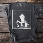 Dark t-shirt with a black and white graphic of a cat sitting with a can and cigarette.