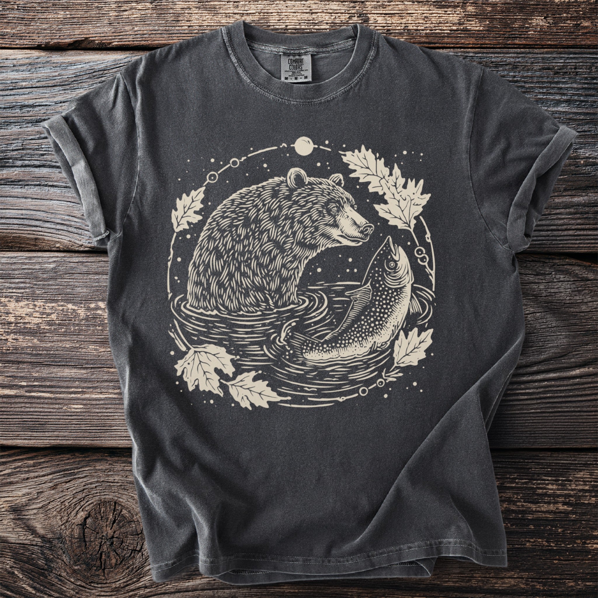Dark t-shirt with a graphic of a bear and fish in water with leaves.