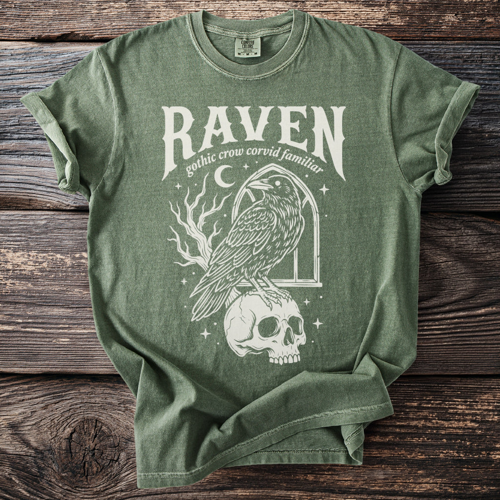 Green t-shirt with a raven perched on a skull, text reads "Raven gothic crow corvid familiar".