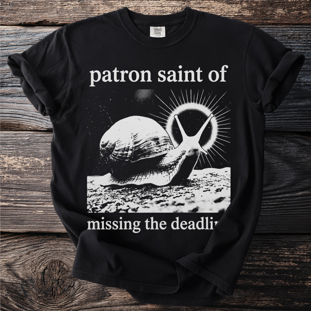 Black t-shirt with text "patron saint of missing the deadli" and a snail graphic.