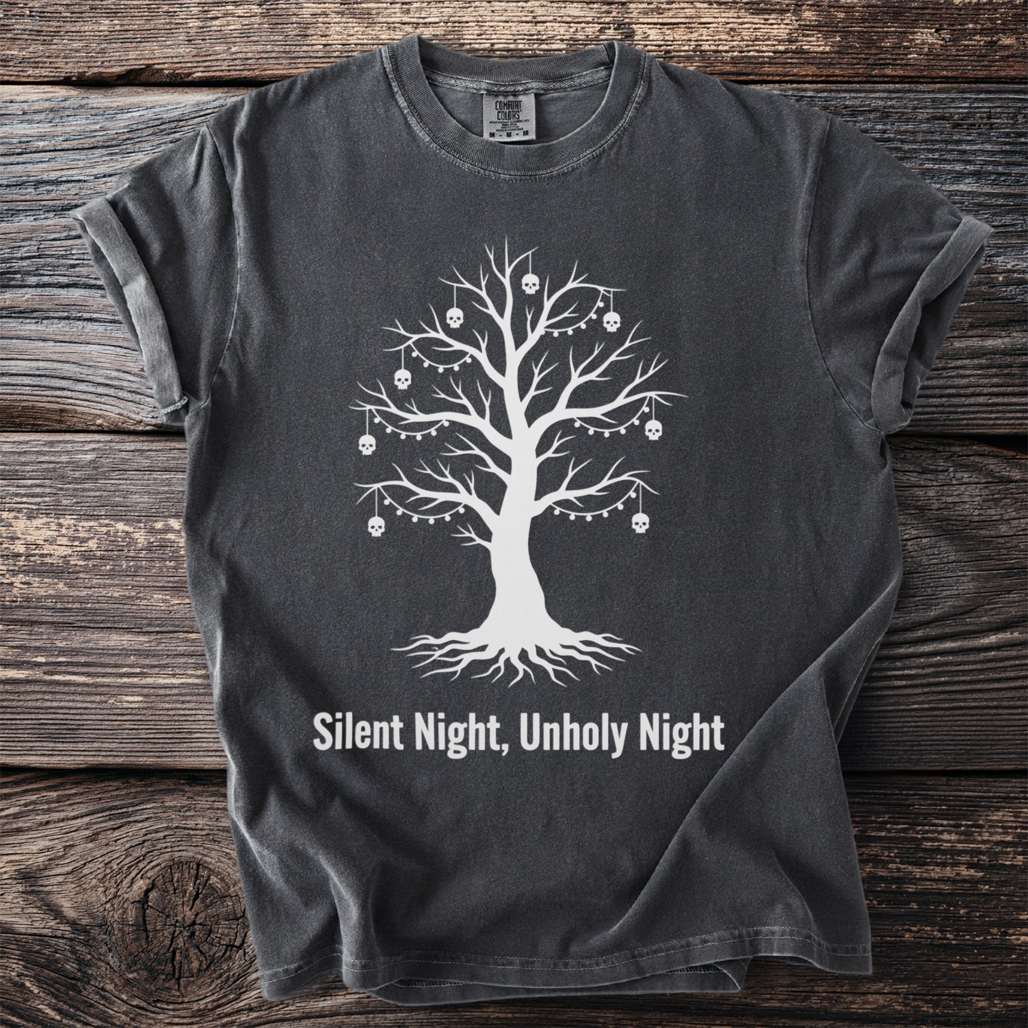 Dark grey t-shirt with white graphic of a tree with skulls and lights, text "Silent Night, Unholy Night".
