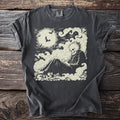 Dark t-shirt with cream-colored graphic of a skeleton sitting on clouds under a full moon with bats.