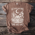 Brown t-shirt with white design of skull, plants, moon, and text: "ALL PLANTS ARE EDIBLE SOME ONLY ONCE".