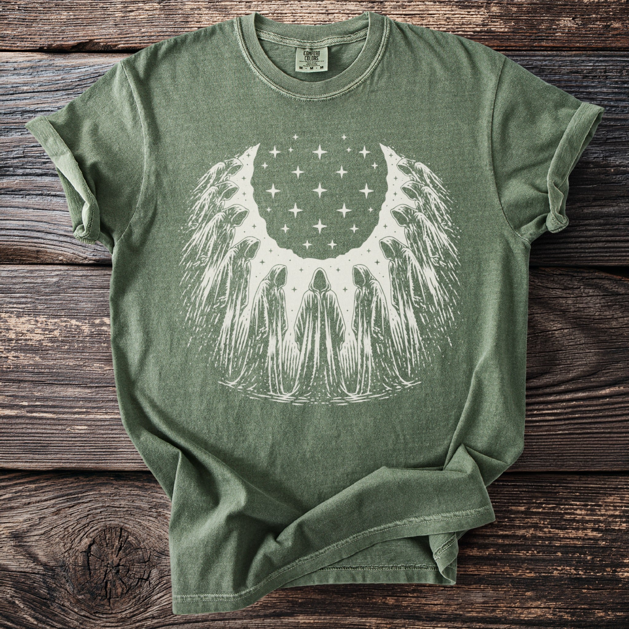 Green t-shirt with a white graphic of hooded figures surrounding stars.